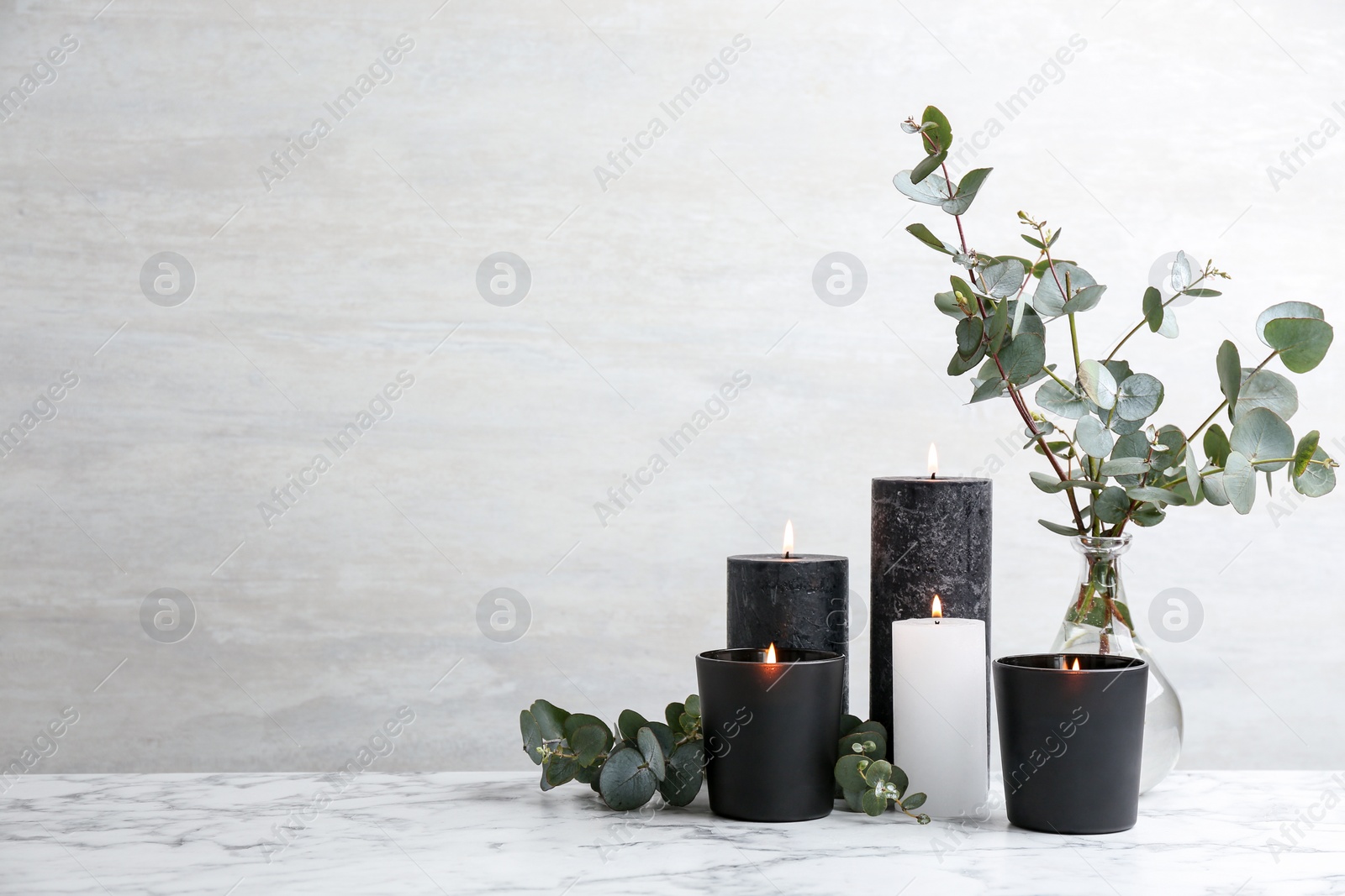 Photo of Burning candles and green branches on marble table, space for text