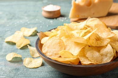 Delicious crispy potato chips in bowl on table, closeup with space for text