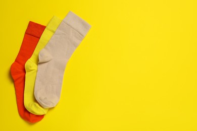 Different socks on yellow background, flat lay. Space for text