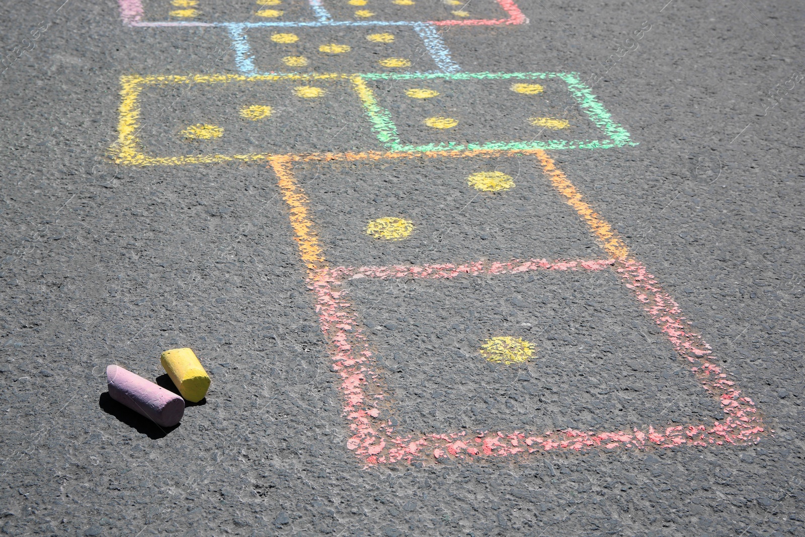 Photo of Hopscotch drawn with colorful chalk on asphalt outdoors, closeup