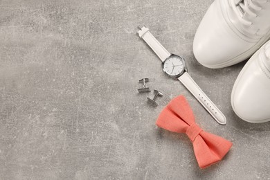 Photo of Stylish pink bow tie, wristwatch, shoes and cufflinks on light grey background, flat lay. Space for text