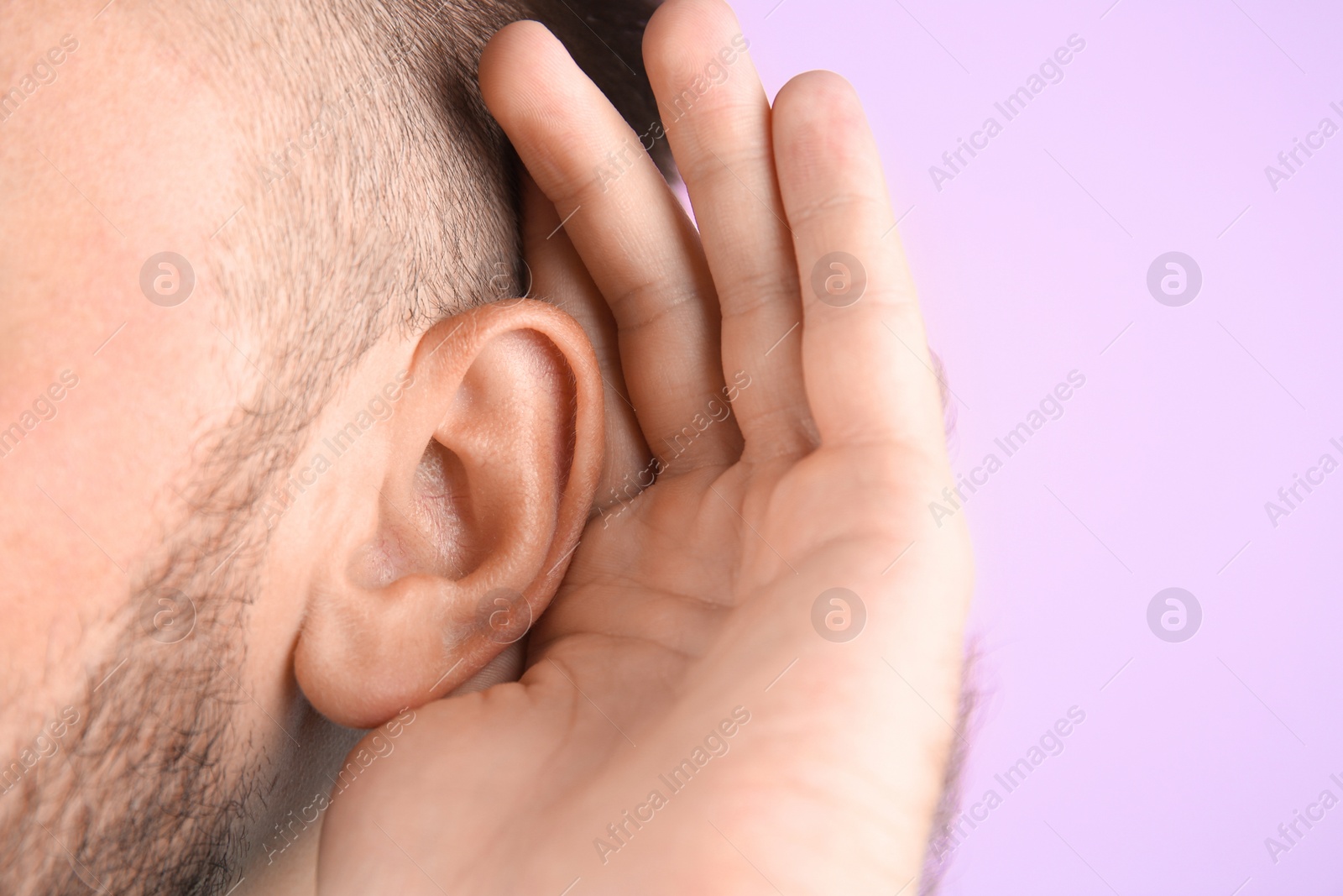 Photo of Young man with hearing problem on color background, closeup