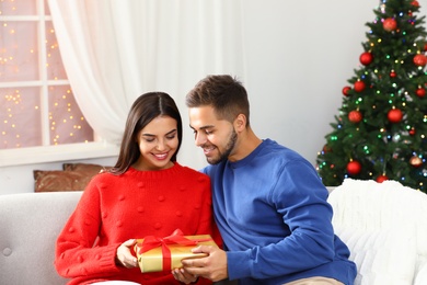 Happy young couple with Christmas gift at home