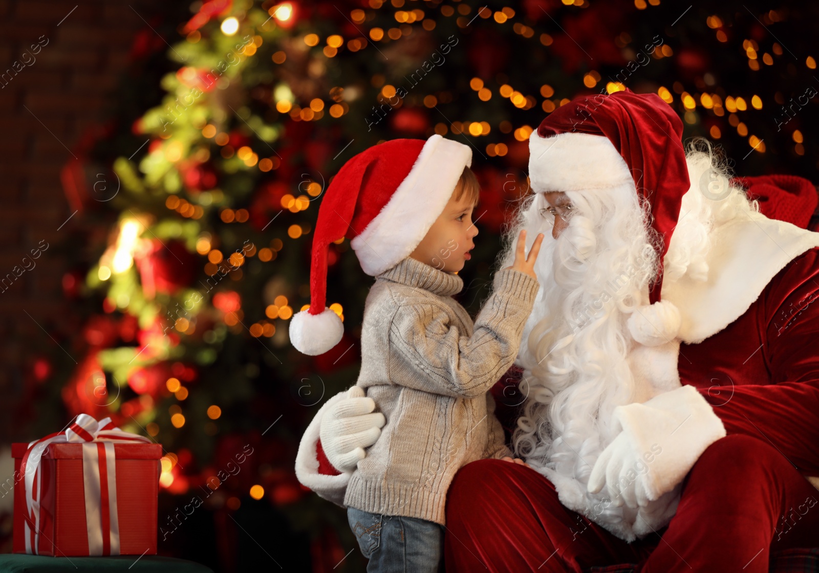 Photo of Santa Claus and little boy near Christmas tree indoors