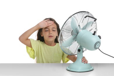 Photo of Little girl suffering from heat in front of fan on white background. Summer season
