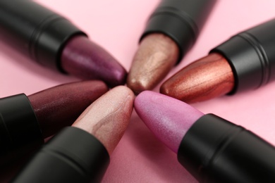 Photo of Set of bright lipsticks in black tubes on pink background