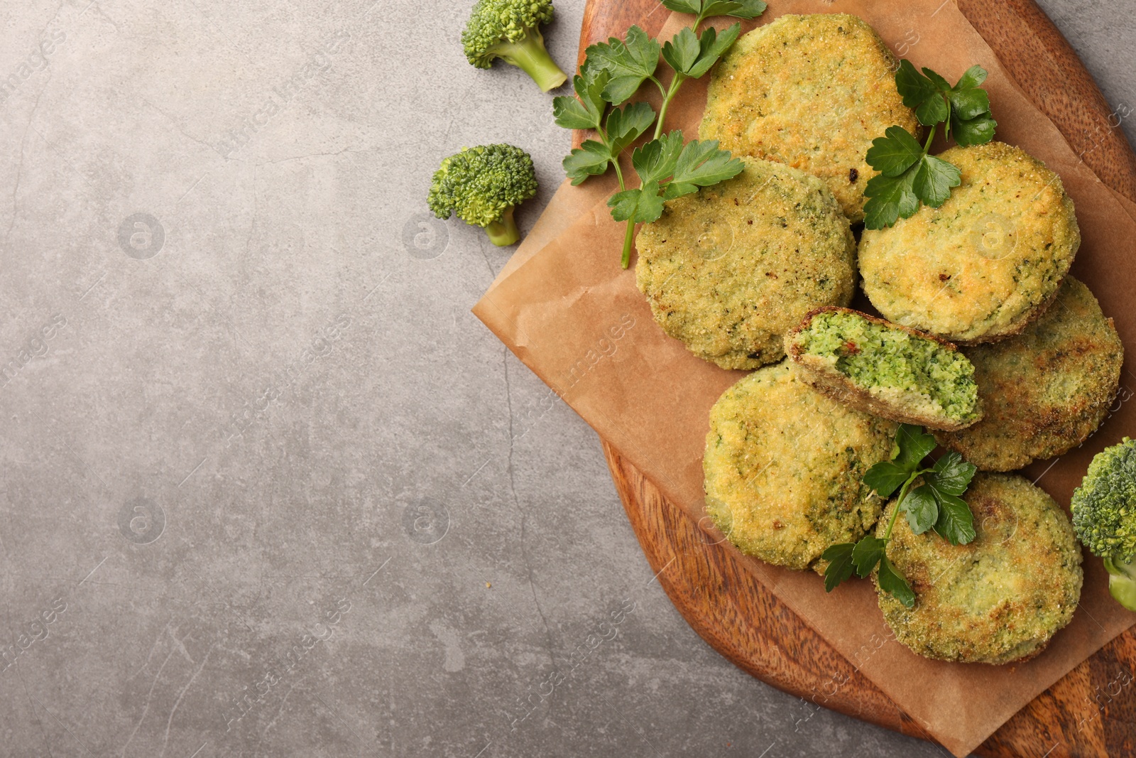 Photo of Delicious vegan cutlets with broccoli and parsley on light gray table, top view. Space for text