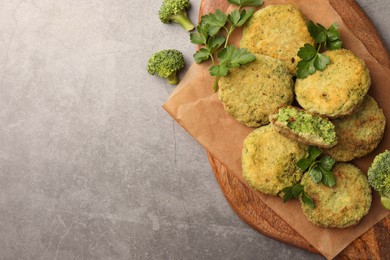 Photo of Delicious vegan cutlets with broccoli and parsley on light gray table, top view. Space for text