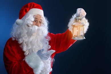Photo of Santa Claus with Christmas lantern on dark blue background
