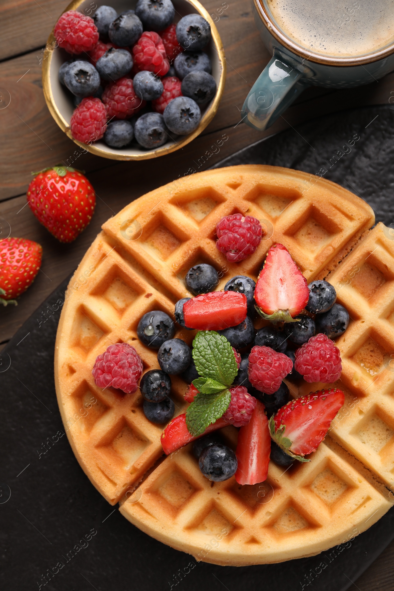 Photo of Tasty Belgian waffle with fresh berries on wooden table, flat lay