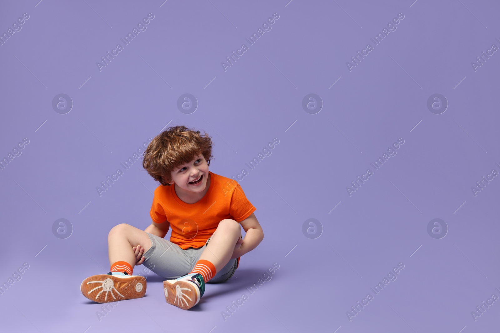 Photo of Happy little boy dancing on violet background. Space for text