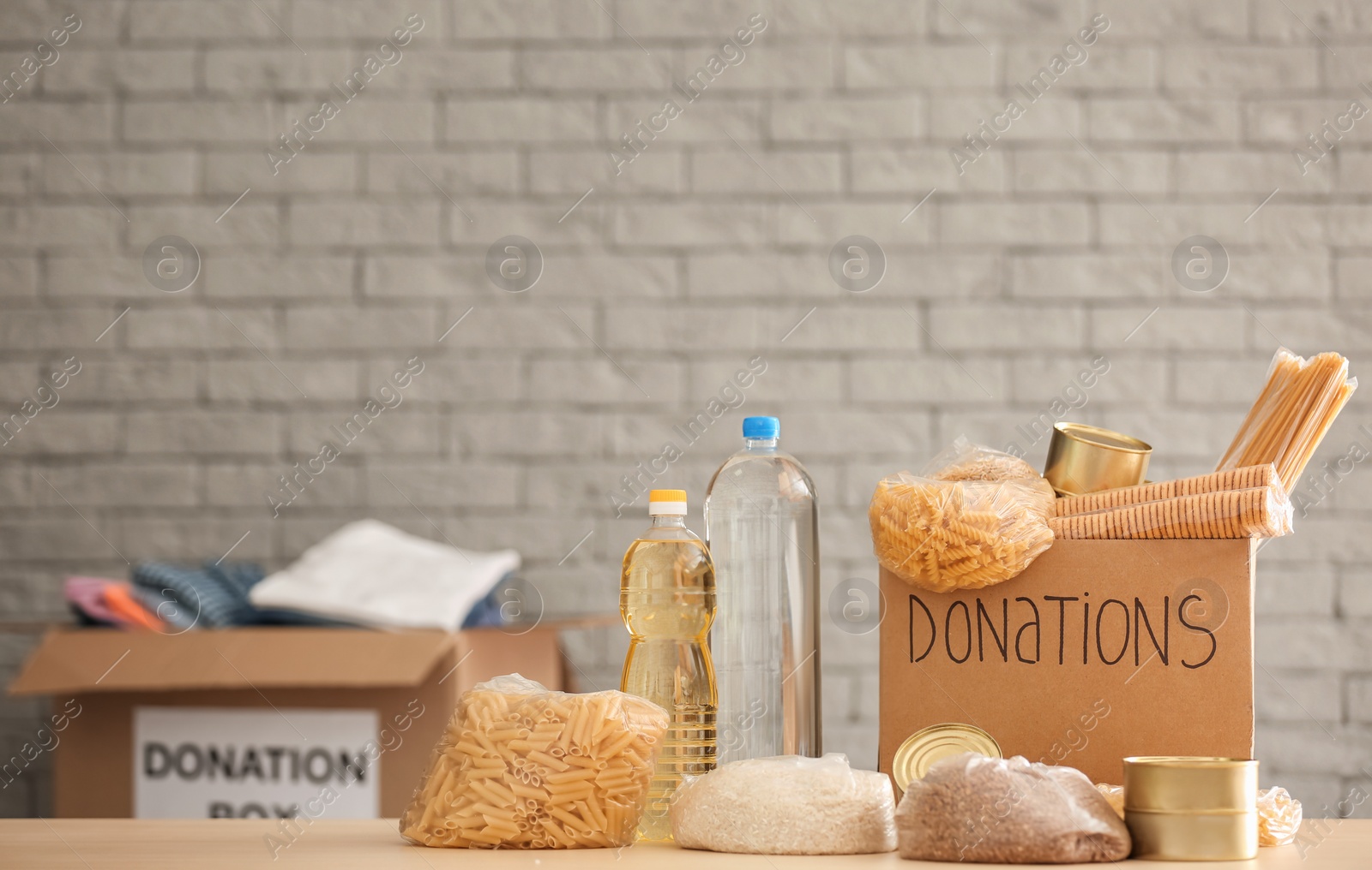 Photo of Donation box with food on table against brick wall