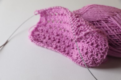 Photo of Knitting, needles and soft pink yarn on light background, closeup