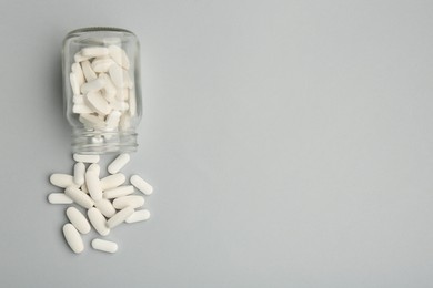 Vitamin pills and bottle on grey background, top view. Space for text