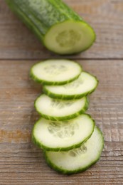 Photo of Cut ripe cucumber on wooden table, closeup