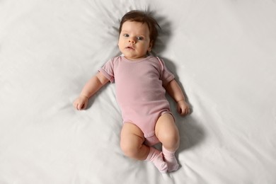 Photo of Cute little baby on cosy bed, top view