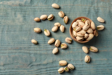 Composition with organic pistachio nuts on wooden table, flat lay. Space for text