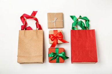 Flat lay composition with shopping bags and gifts on white background