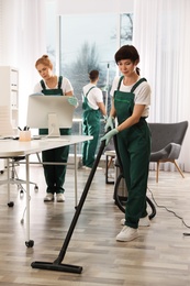 Photo of Team of professional janitors working in modern office. Cleaning service