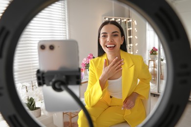 Photo of Blogger recording video in dressing room at home, view through ring lamp