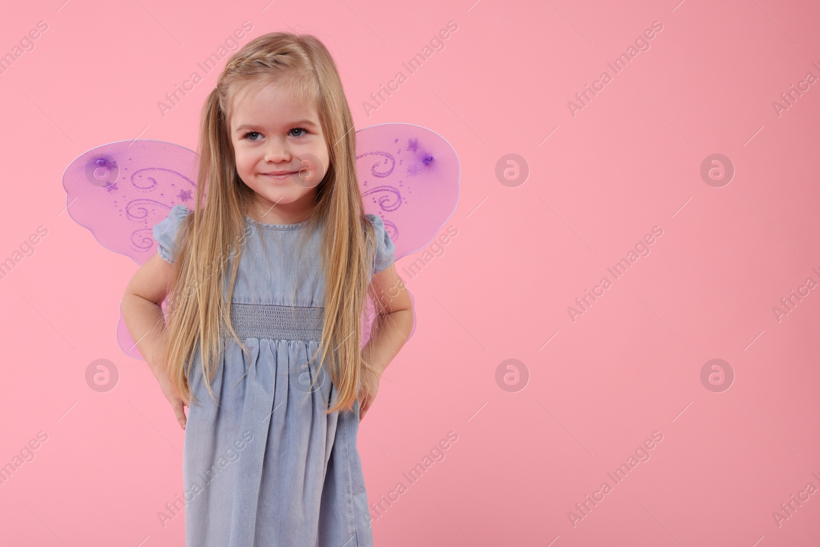 Photo of Cute little girl in fairy costume with violet wings on pink background, space for text