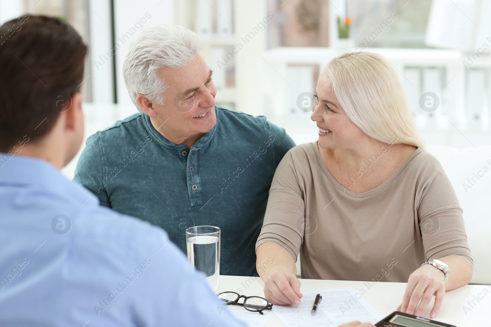 Photo of Mature couple discussing pension with consultant in office