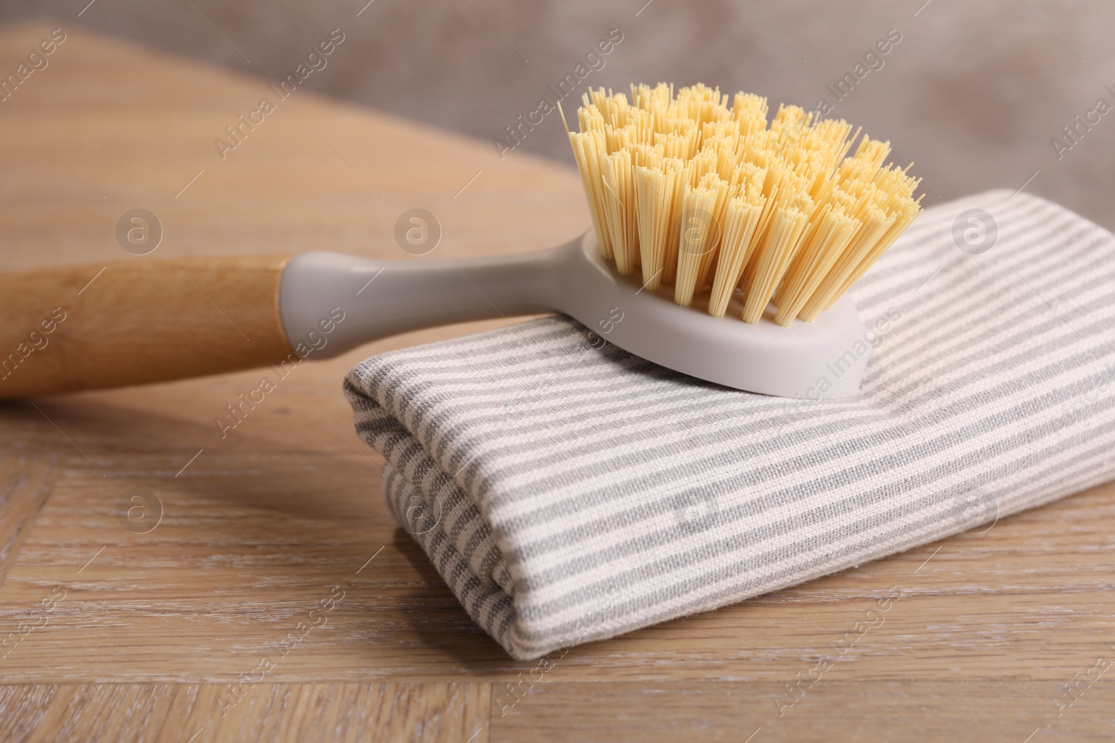 Photo of One cleaning brush and rag on wooden table, closeup