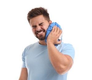 Young man with cold compress suffering from neck pain on white background