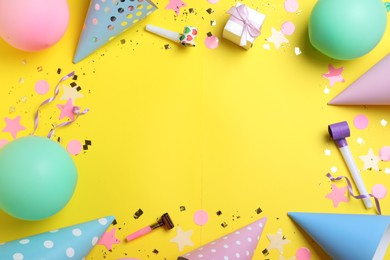 Photo of Frame made of party hats and birthday decor on yellow background, flat lay. Space for text.