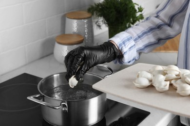 Woman cooking delicious dumplings in kitchen, closeup