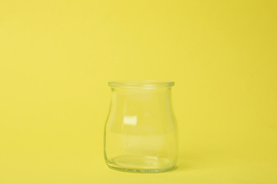 Open empty glass jar on light yellow background