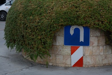 Photo of U-Turn road sign near green bush in city