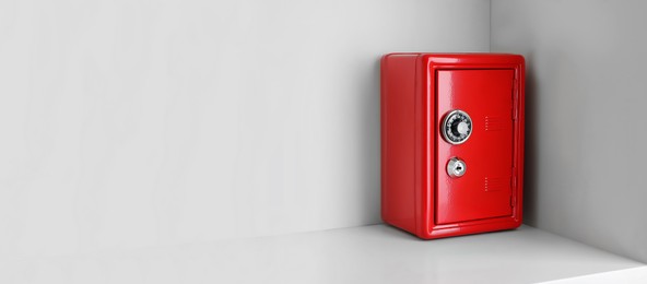 Image of Red steel safe with mechanical combination lock on shelf, space for text. Banner design