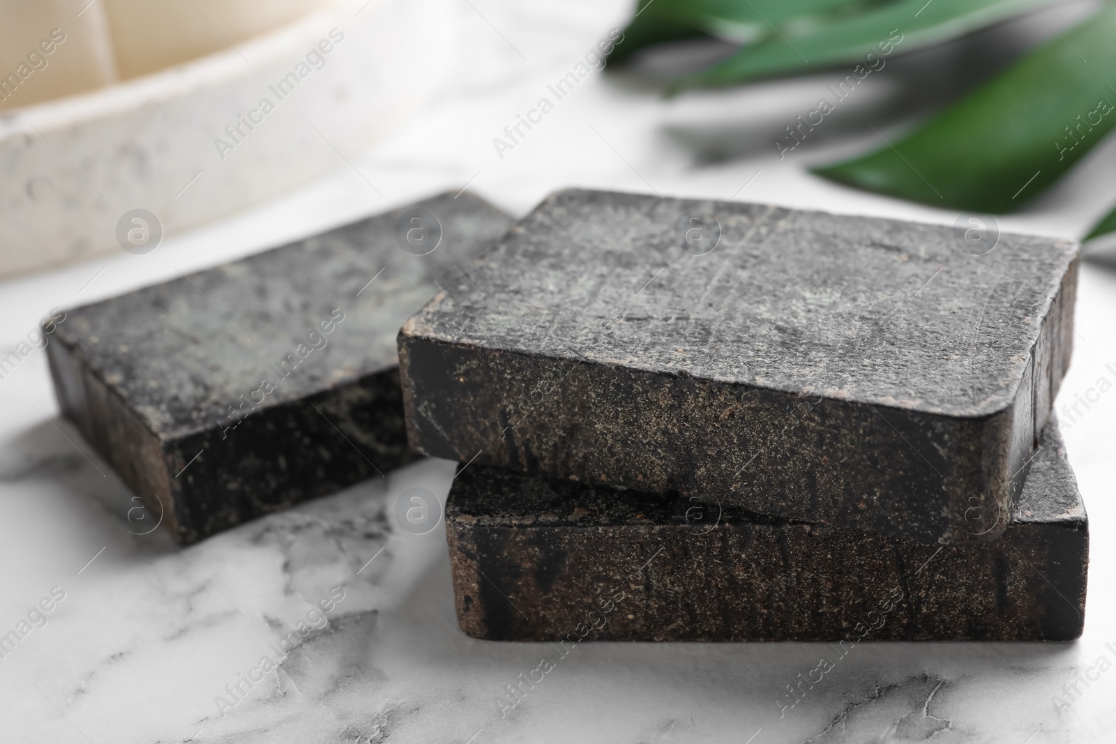 Photo of Natural tar soap on white marble table, closeup