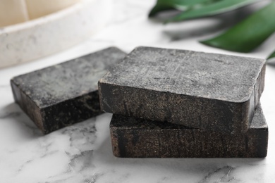 Natural tar soap on white marble table, closeup