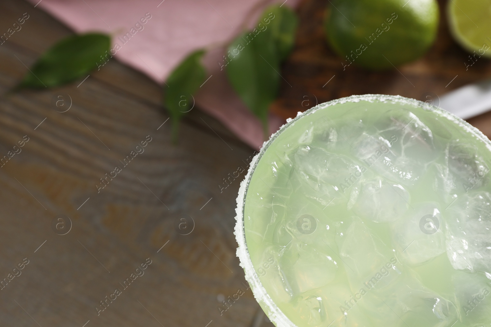 Photo of Delicious Margarita cocktail in glass on wooden table, top view. Space for text