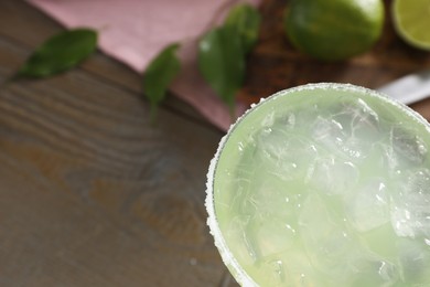 Delicious Margarita cocktail in glass on wooden table, top view. Space for text