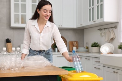 Photo of Smiling woman separating garbage in kitchen. Space for text