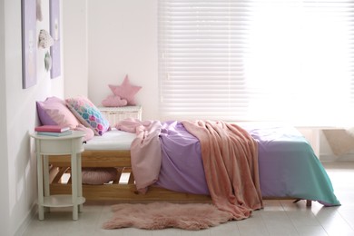 Bed with colorful linen in stylish children's room. Interior design