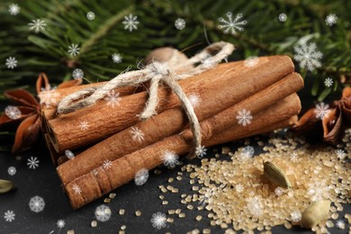 Different spices and fir tree branches on dark table, closeup. Cinnamon, anise, cardamom