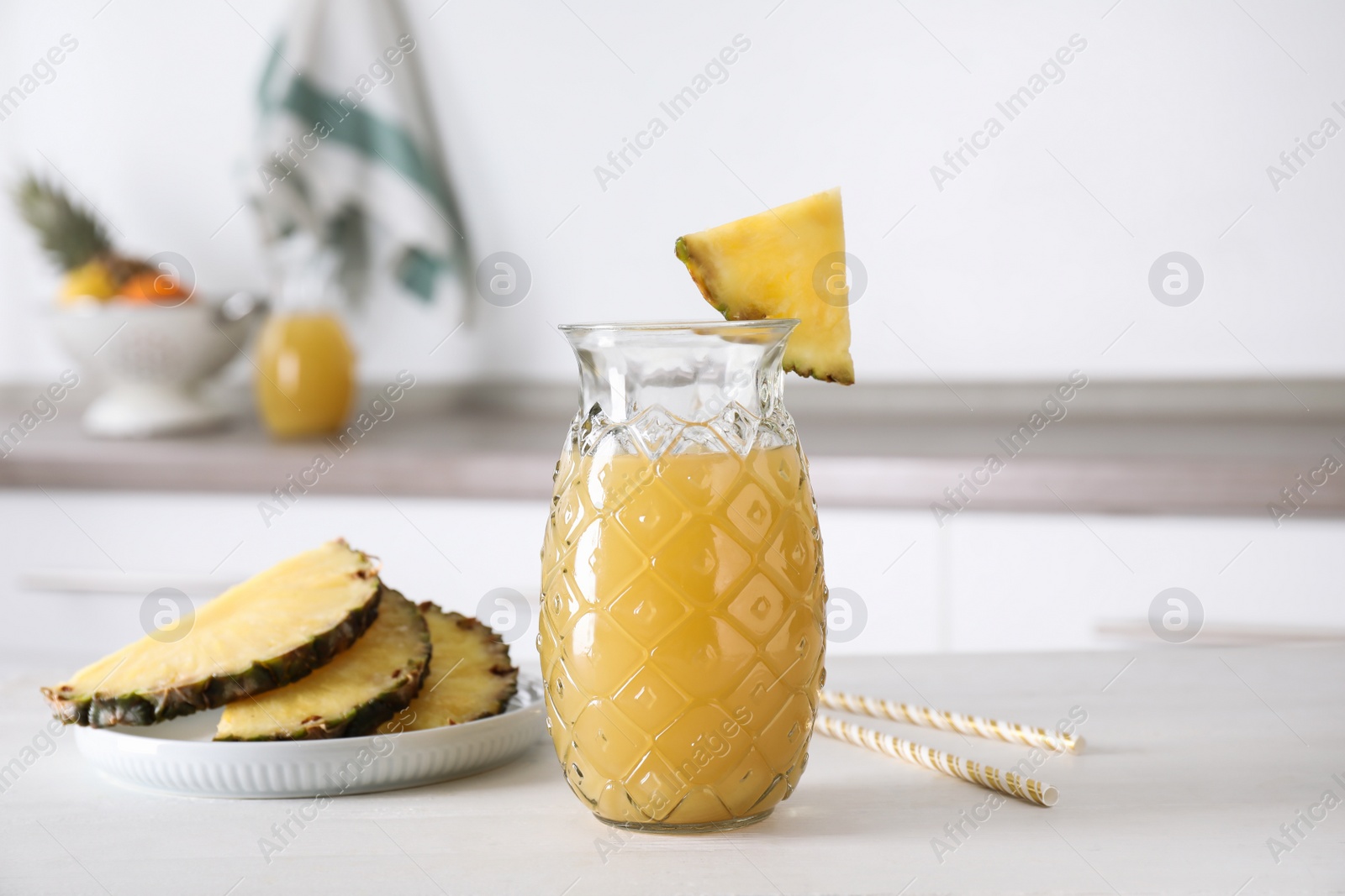 Photo of Delicious pineapple juice and fresh fruit on white table indoors
