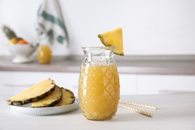 Delicious pineapple juice and fresh fruit on white table indoors