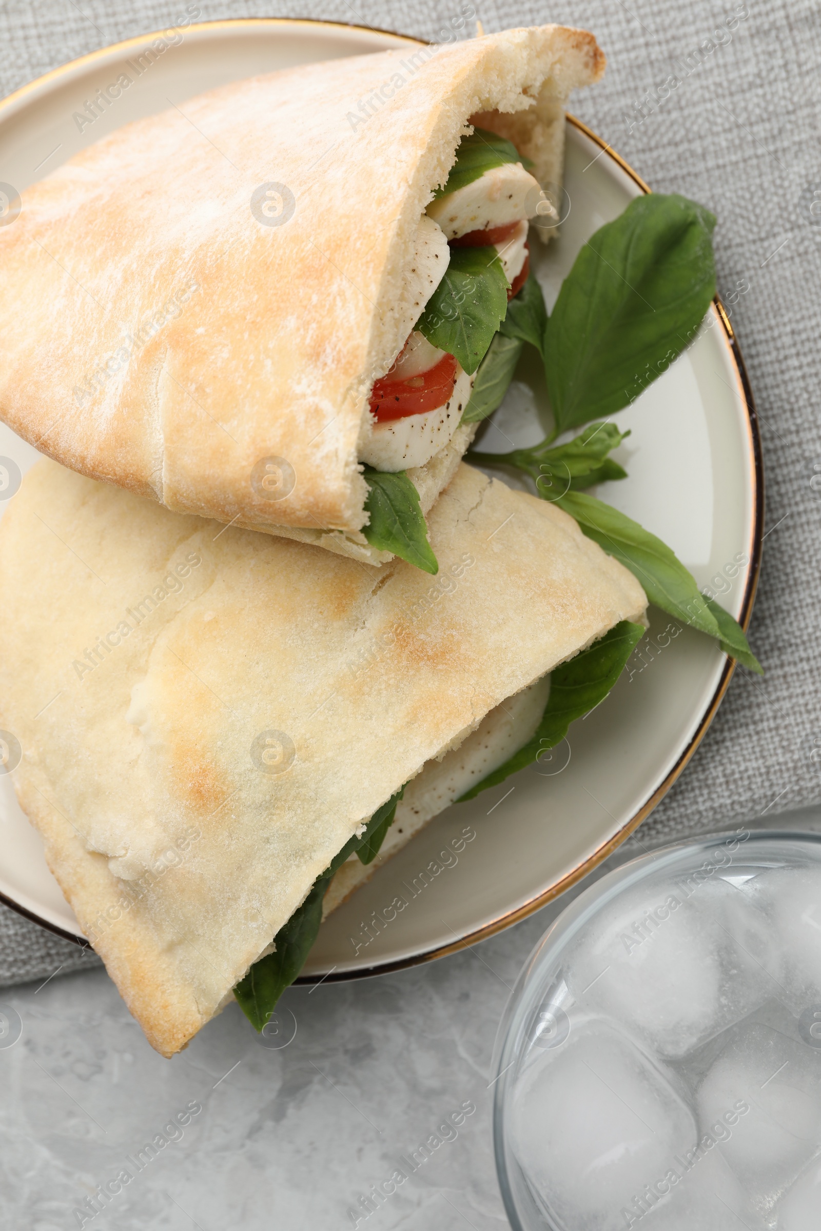 Photo of Delicious pita sandwiches with mozzarella, tomatoes and basil on light grey marble table, flat lay