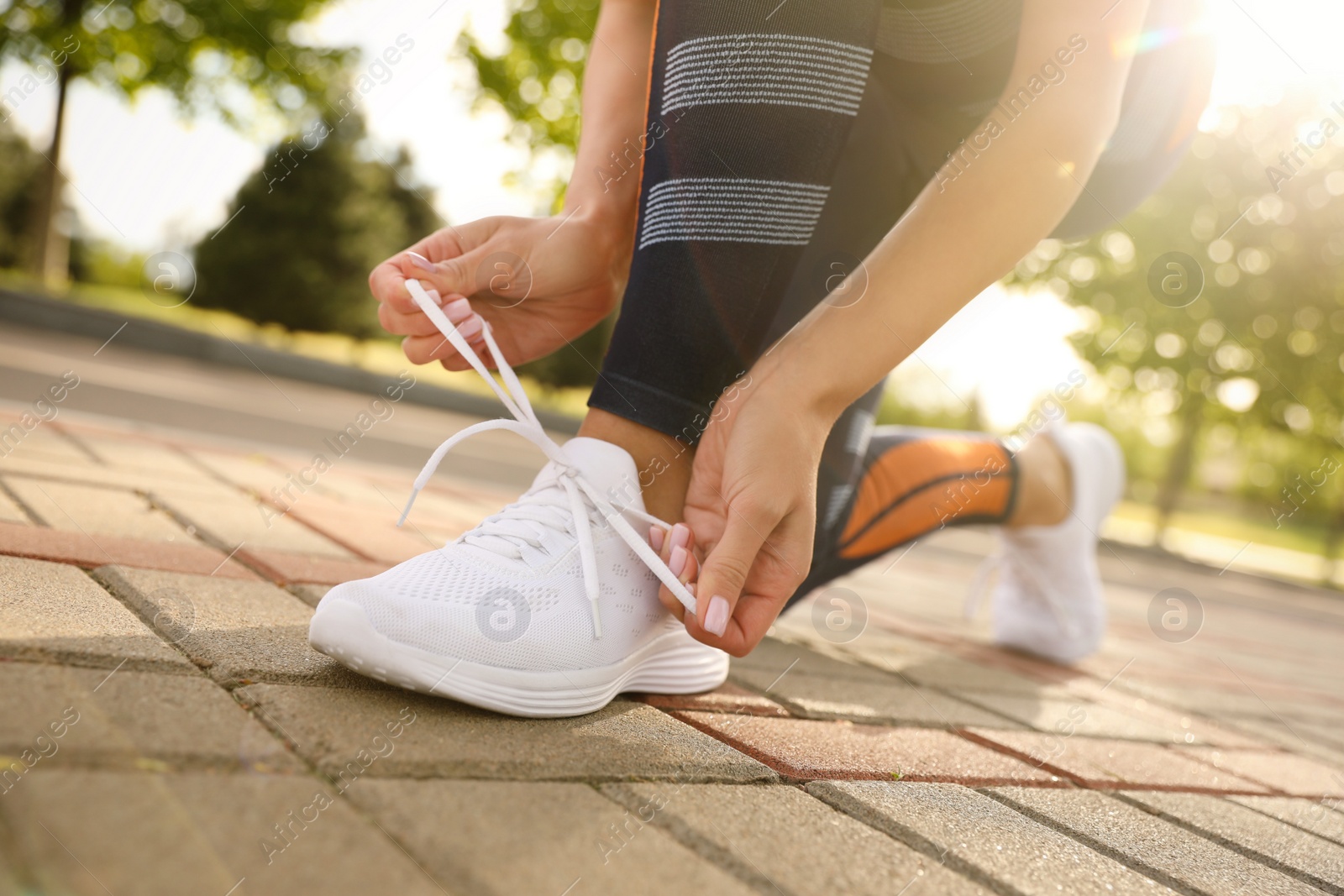 Photo of Woman tying laces of sneakers outdoors, closeup. Morning fitness