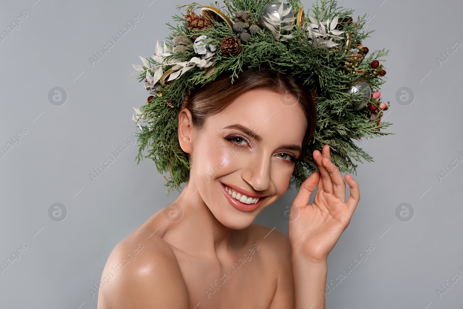 Photo of Beautiful young woman wearing Christmas wreath on grey background