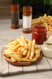 Photo of Delicious french fries served with sauces on light wooden table