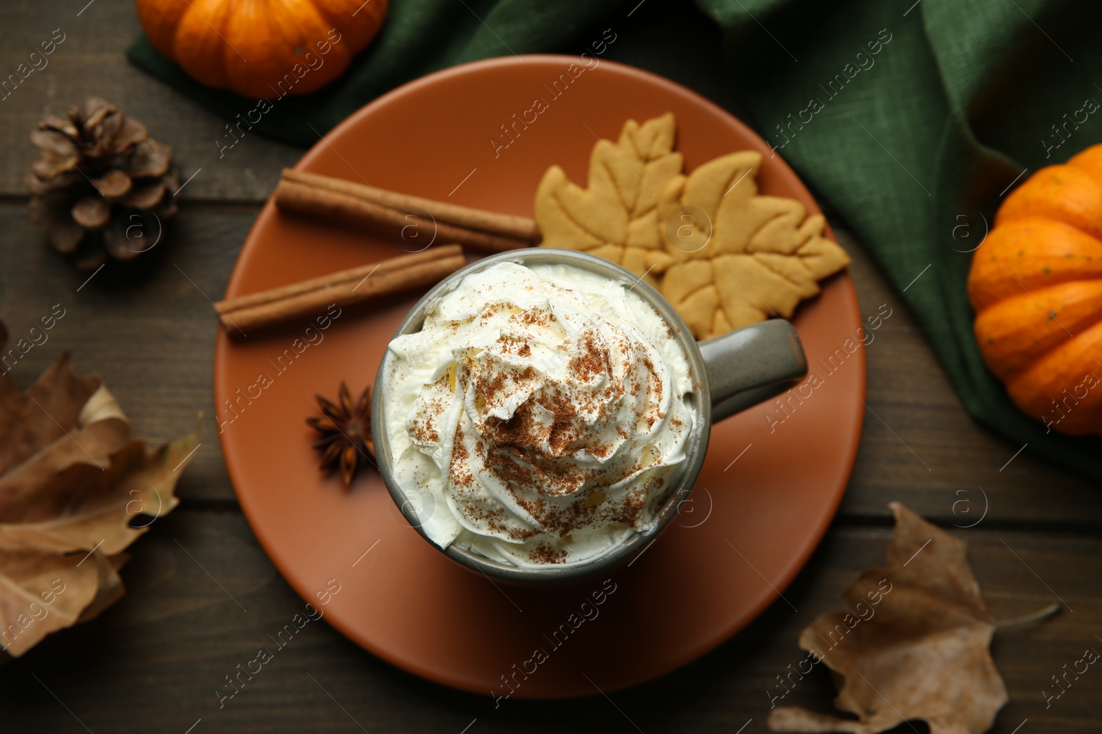 Photo of Flat lay composition of tasty pumpkin spice latte with whipped cream in cup on wooden table