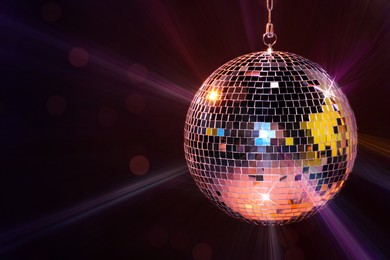 Image of Shiny bright disco ball on dark background, space for text