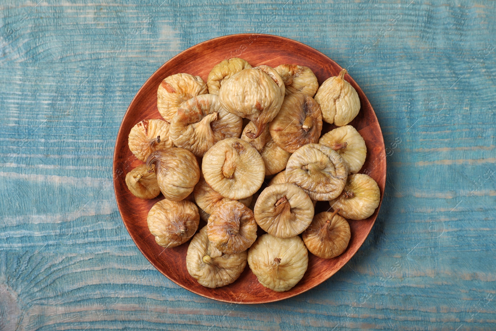 Photo of Tasty dried figs on light blue wooden table, top view