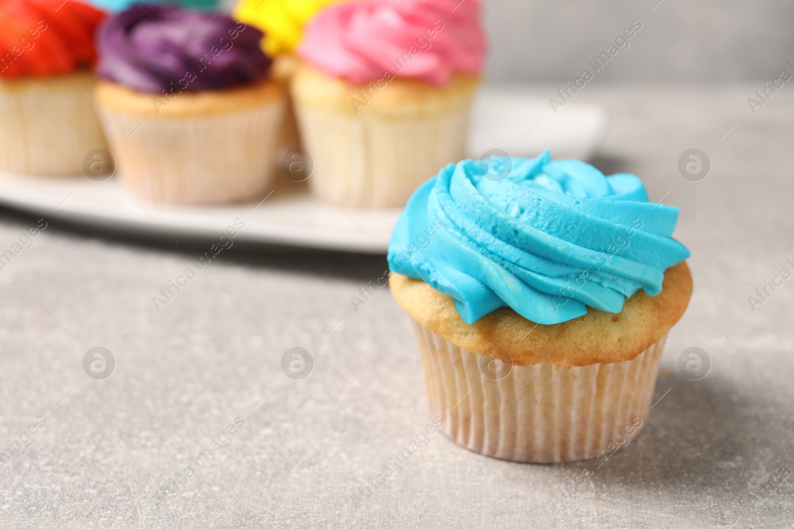 Photo of Delicious cupcakes with bright cream on gray table, selective focus